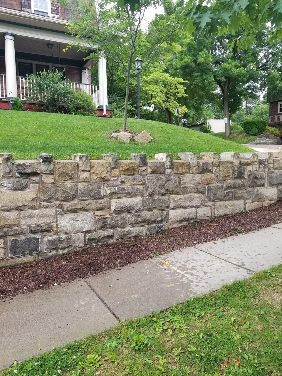 Natural stone retaining wall along sidewalk